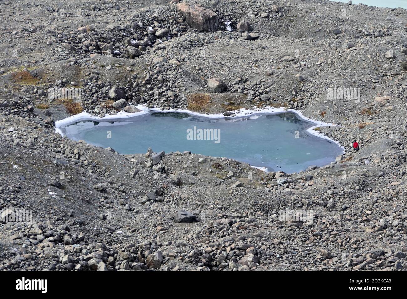 Aerial view of a small half frozen blue lake surrounded by a stony landscape Stock Photo