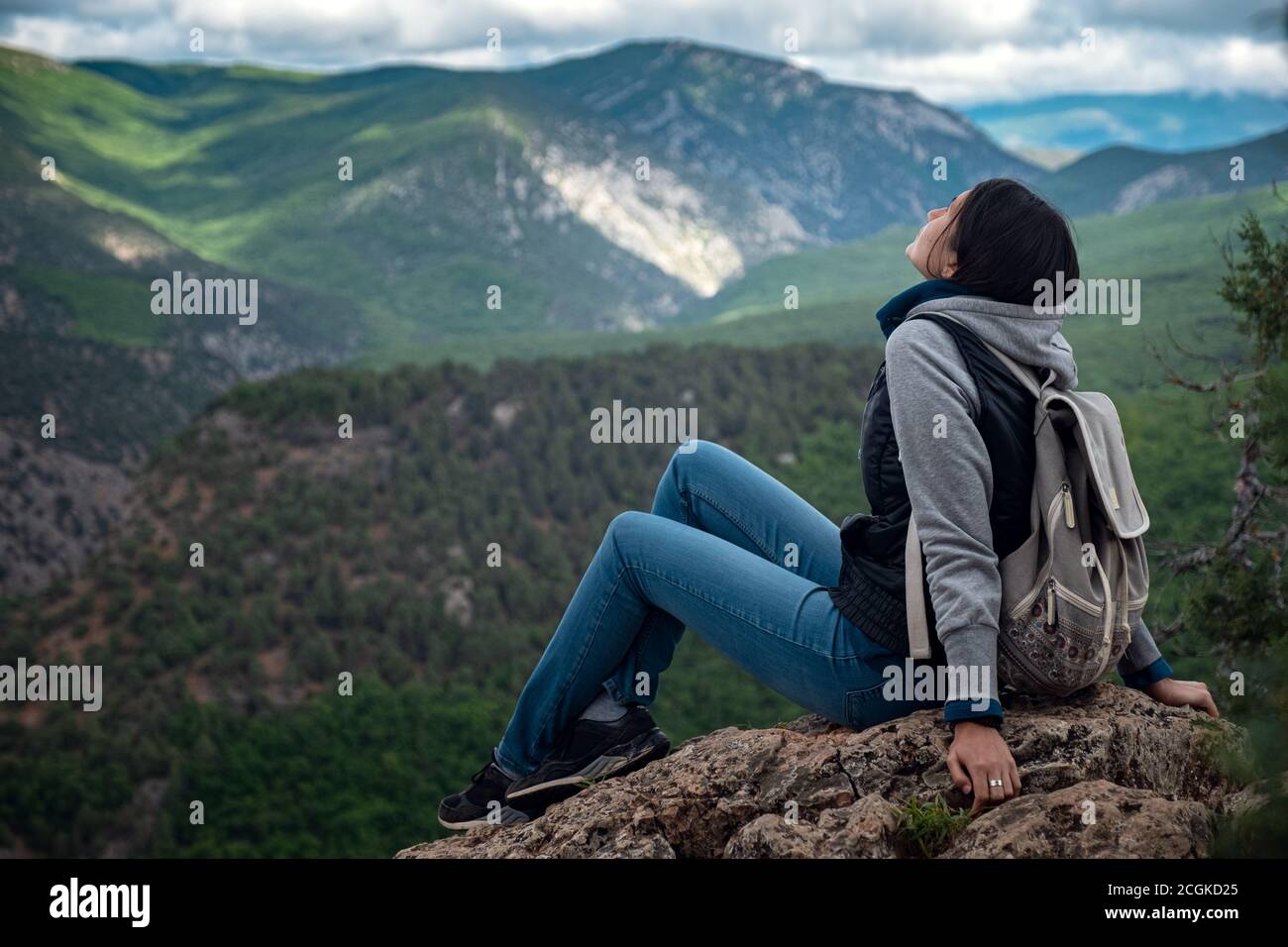 Young traveling woman with a backpack and sitting on top of the ...