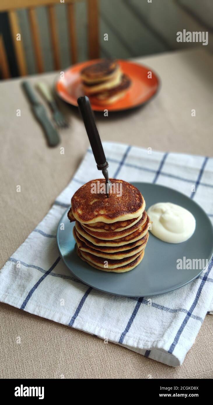Plate with stack of homemade pancakes and sour cream on wooden table, selective focus Stock Photo