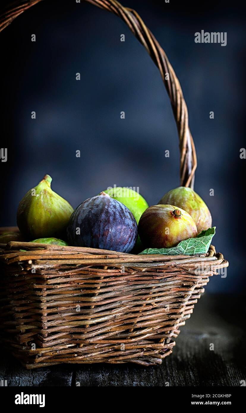 Fresh figs in wicker basket. Closeup. Blurry background. Stock Photo