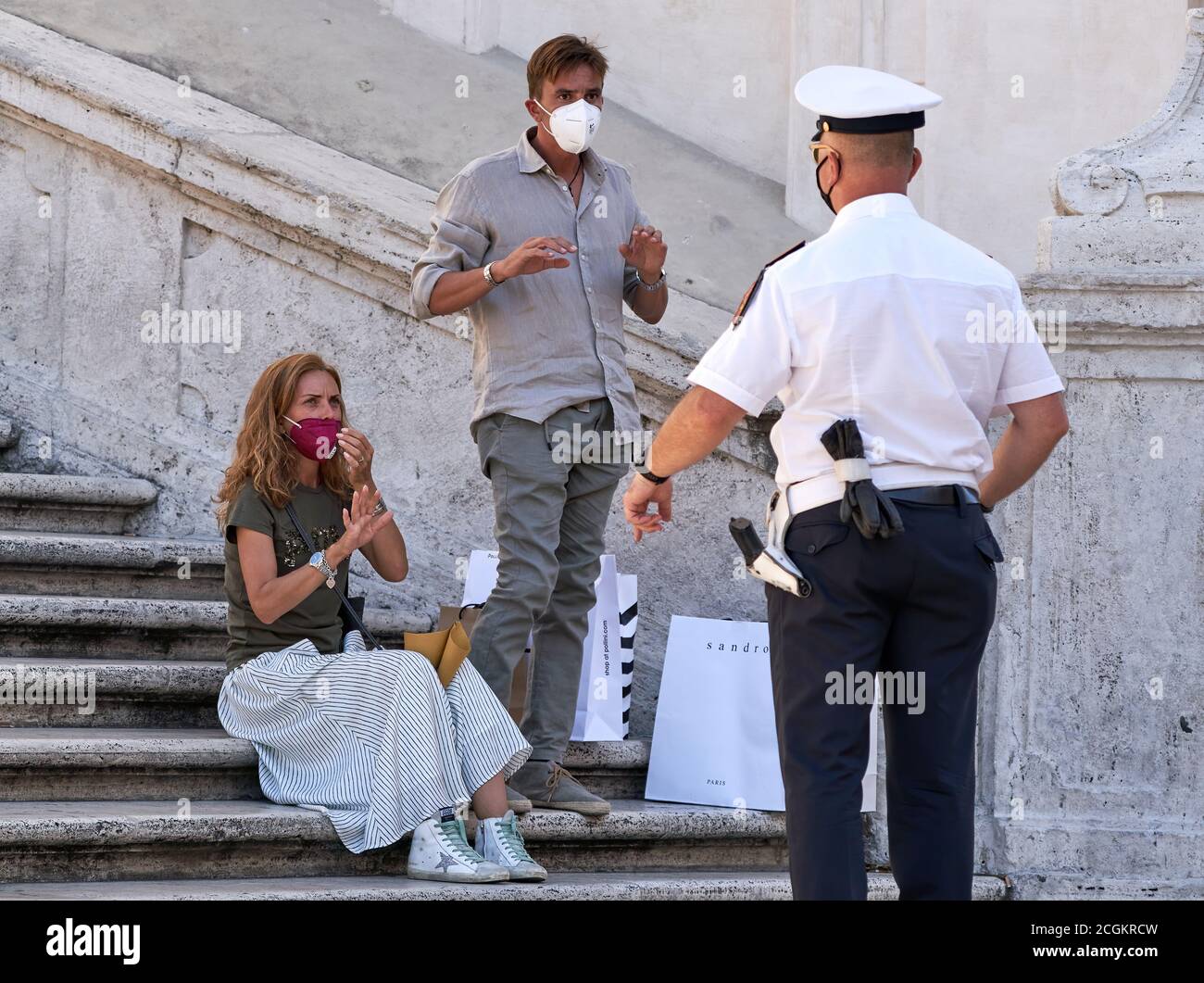 Tourism in Rome: Armed City Police Officer Informs Young Tourist Couple That Sitting on the Famous Spanish Steps is Prohibited by Local Law Stock Photo