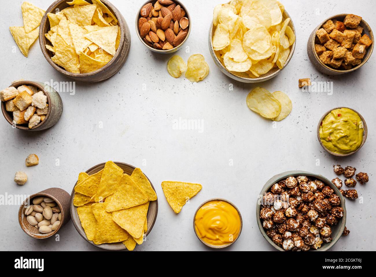 Veraity bowls of beer snacks and sauces on stone table. Nuts, chips, nachos, crackers. Top view with copyspace Stock Photo