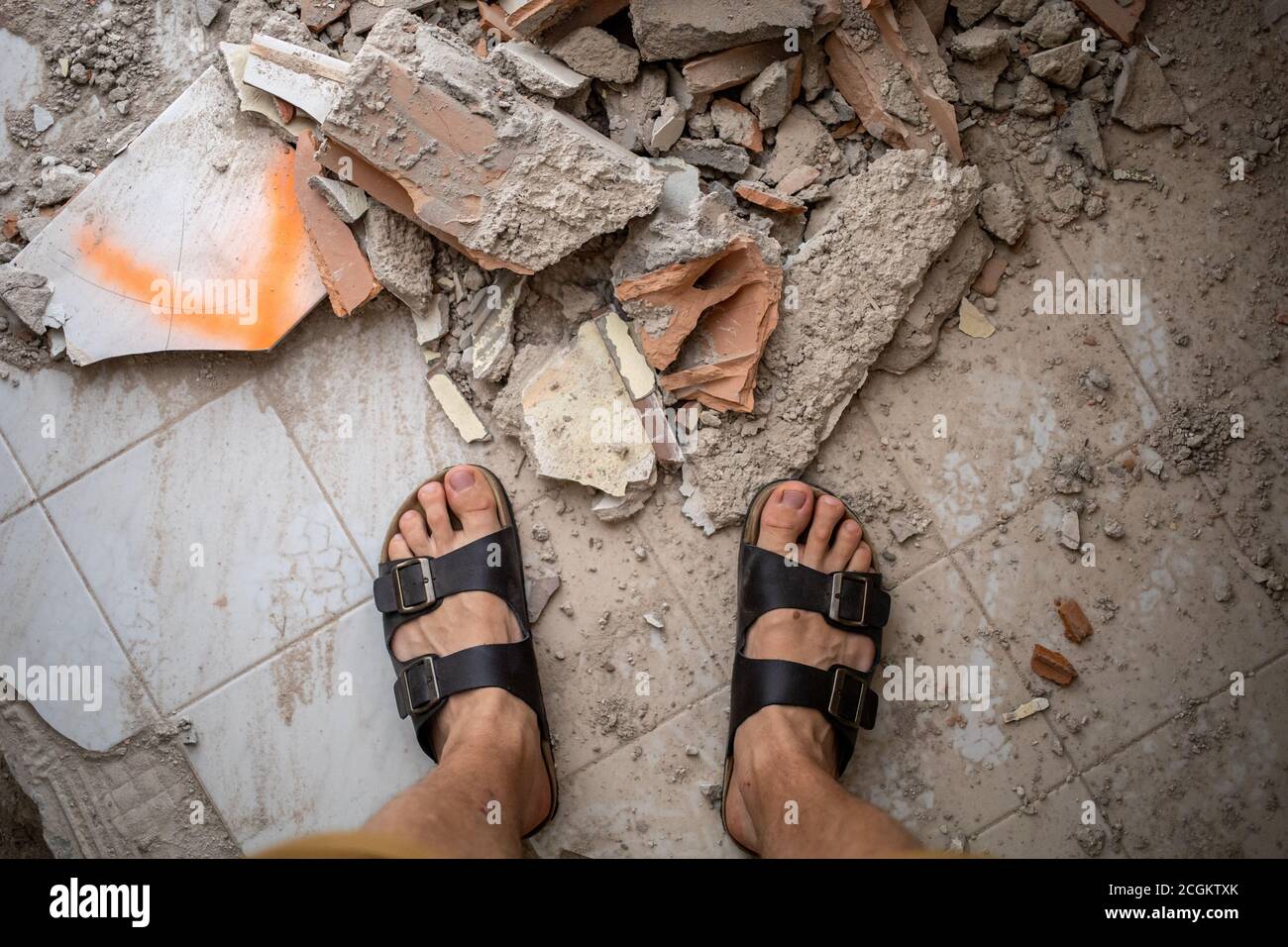 male feet in sandals over pile of building trash Stock Photo - Alamy