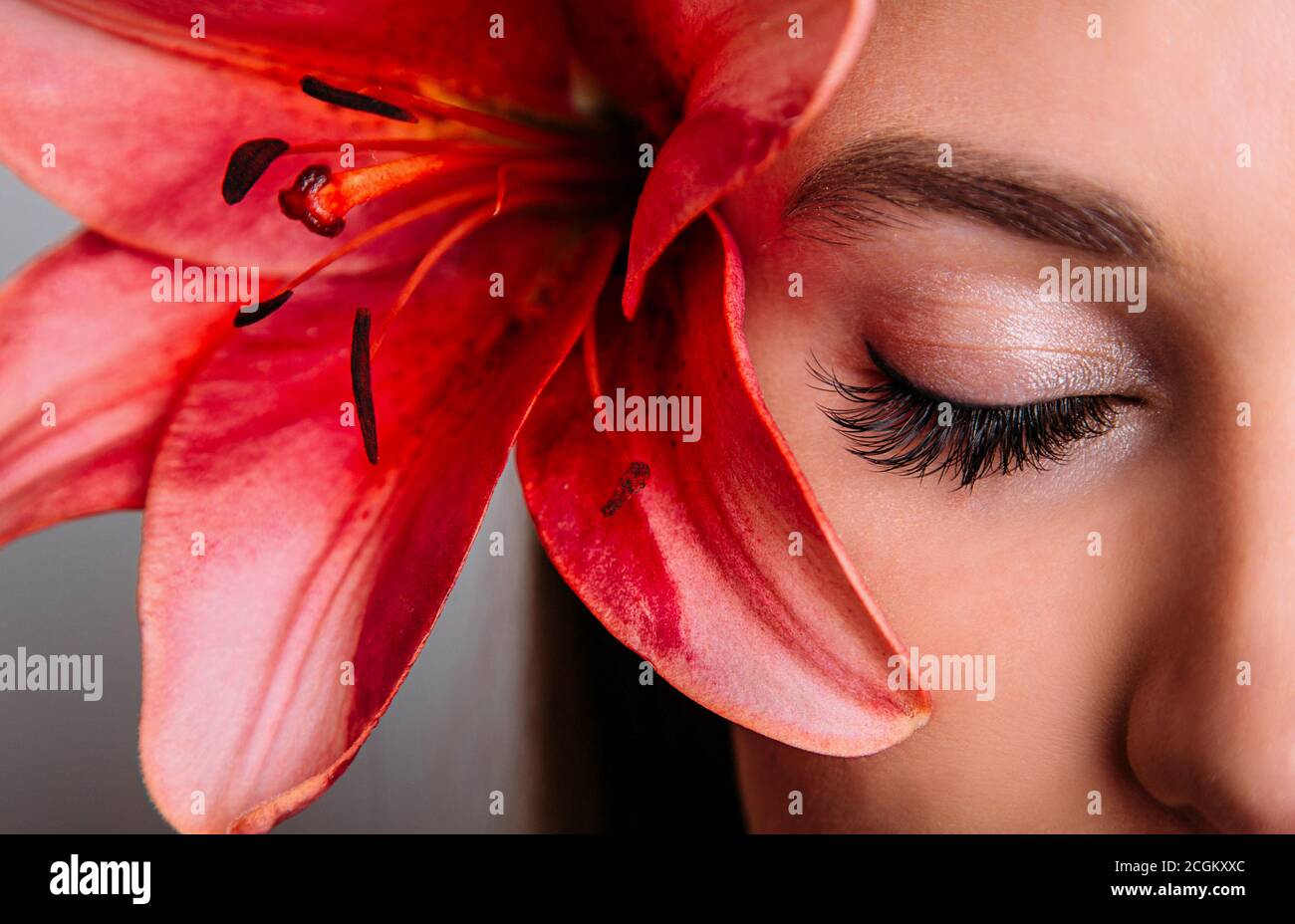 A beautiful eye with extended eyelashes. Fashion girl with lily flower Stock Photo