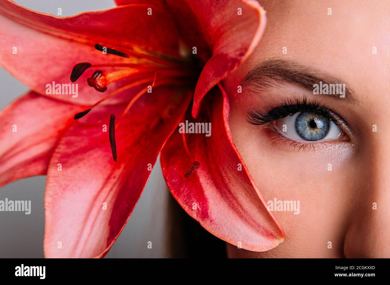 A beautiful eye with extended eyelashes. Fashion girl with lily flower Stock Photo