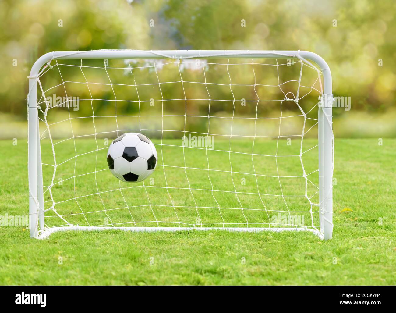 Generic football (soccer) ball hits net of mini goal as concept of recreational sport and family fun Stock Photo