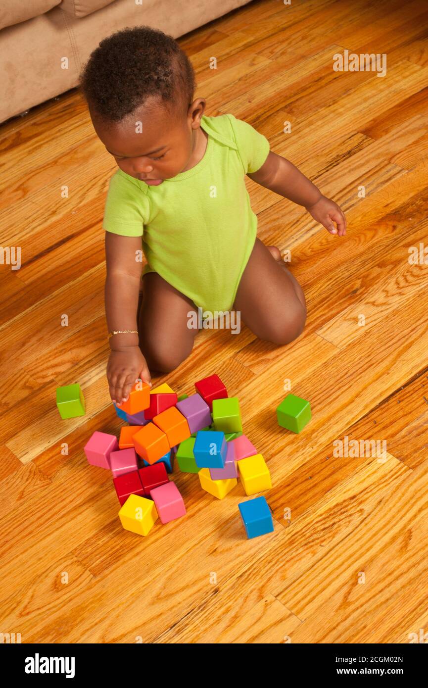 12 month old baby boy kneeling playing with wooden blocks, stacking two blocks Stock Photo