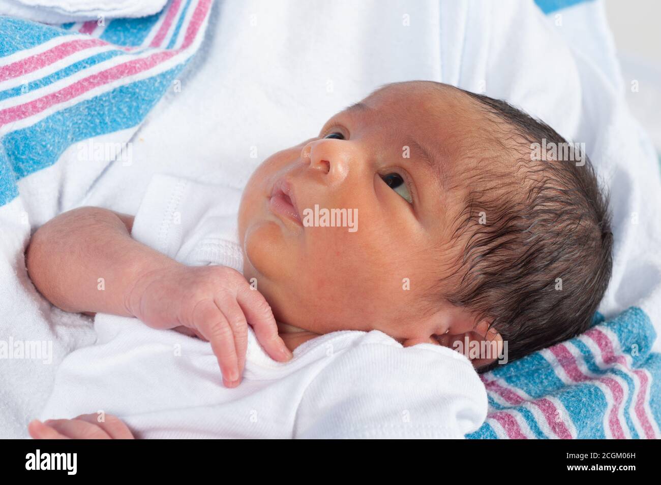Newborn baby boy, 1 week old, closeup, held, looking up, skin slightly yellow from jaundice common in newborns Stock Photo