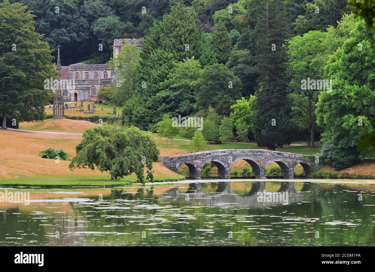 St Peter's Church, the Bristol High Cross and the Palladian Bridge viewed from across the lake on the Stourhead Estate, near Mere, Wiltshire, England Stock Photo