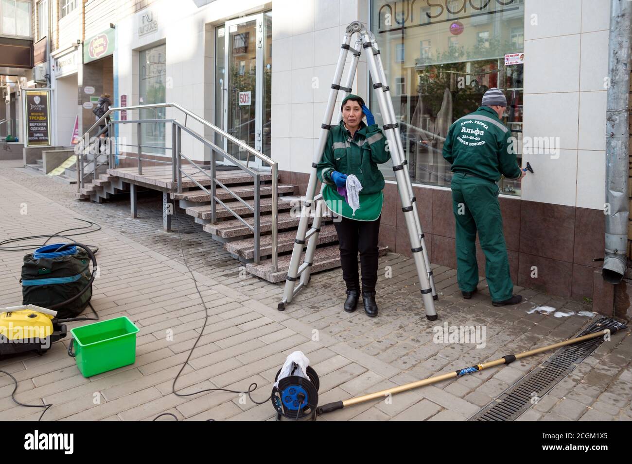 Workers of the cleaning company are cleaning the facade  and engaged in washing windowsafter repairing an office in the center of Krasnoyarsk. Stock Photo