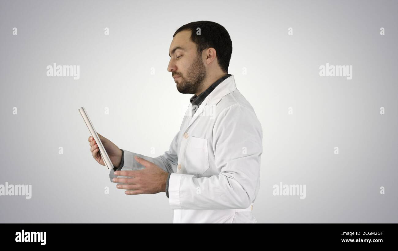 Young Doctor Video Chatting On Tablet on gradient background. Stock Photo