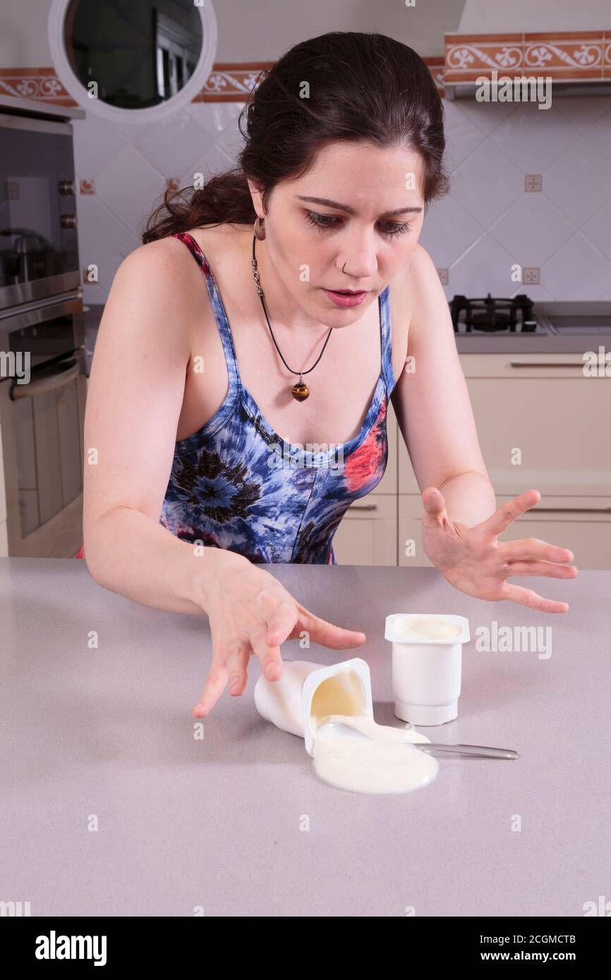 Pretty young woman cleaning yoghurt accidentally spilt Stock Photo
