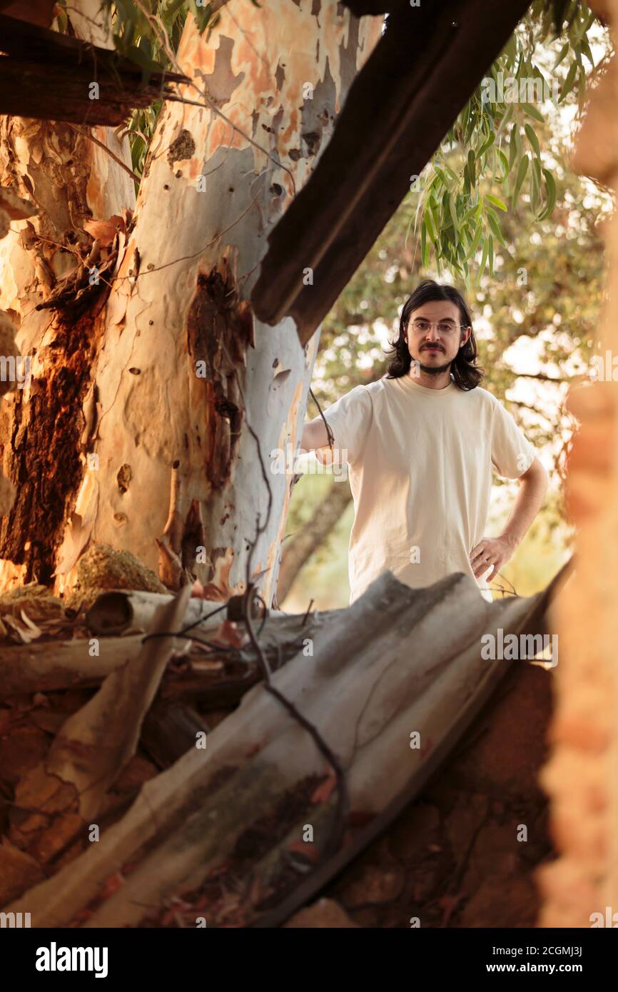 Long Hair Man in White Behind the Tree Stock Photo
