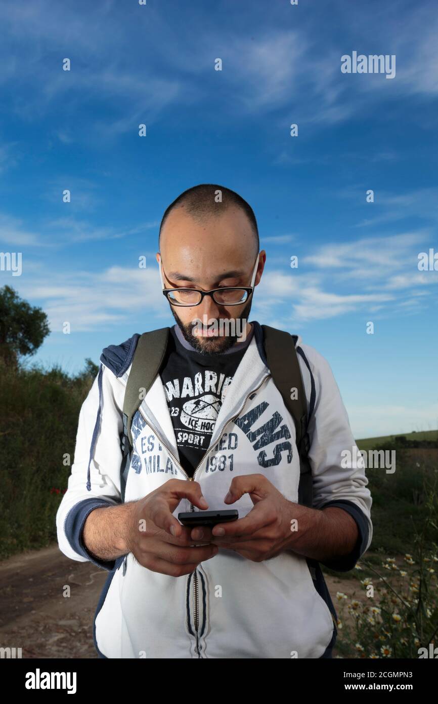 Yound adult male holding a cellphone in a rural enviroment. Stock Photo