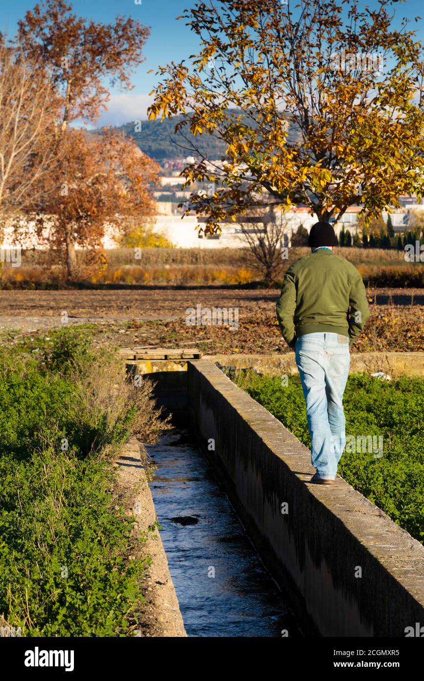 Man walking on a ditch in a rural scene. Stock Photo