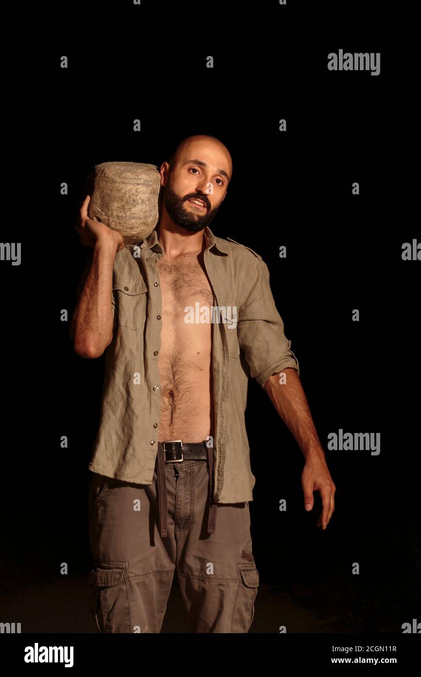 Sexy adult caucasian male carrying a heavy rock Stock Photo
