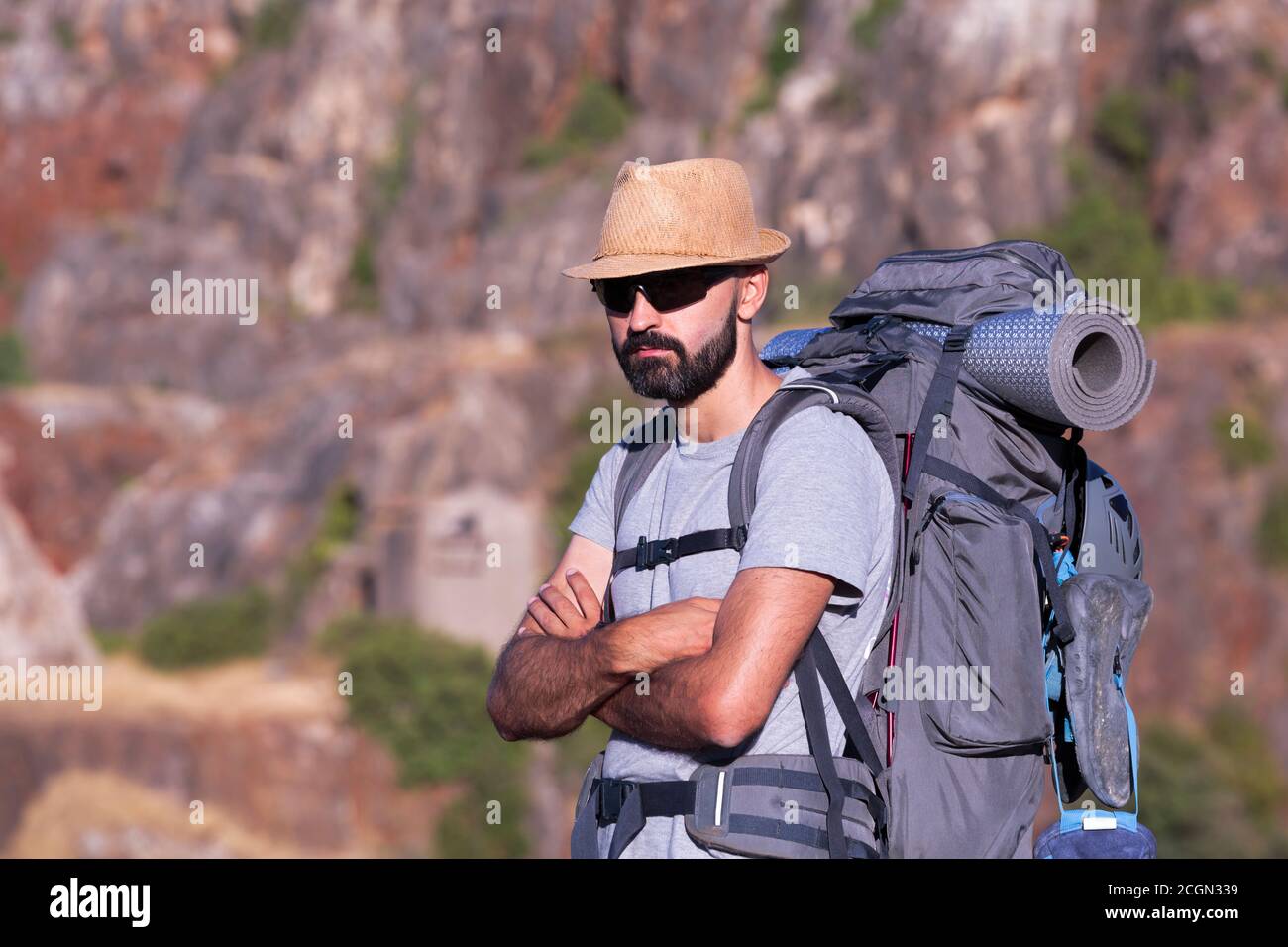 Horizontal view of a hispanic male trekker with sunglasses and a full backpack Stock Photo