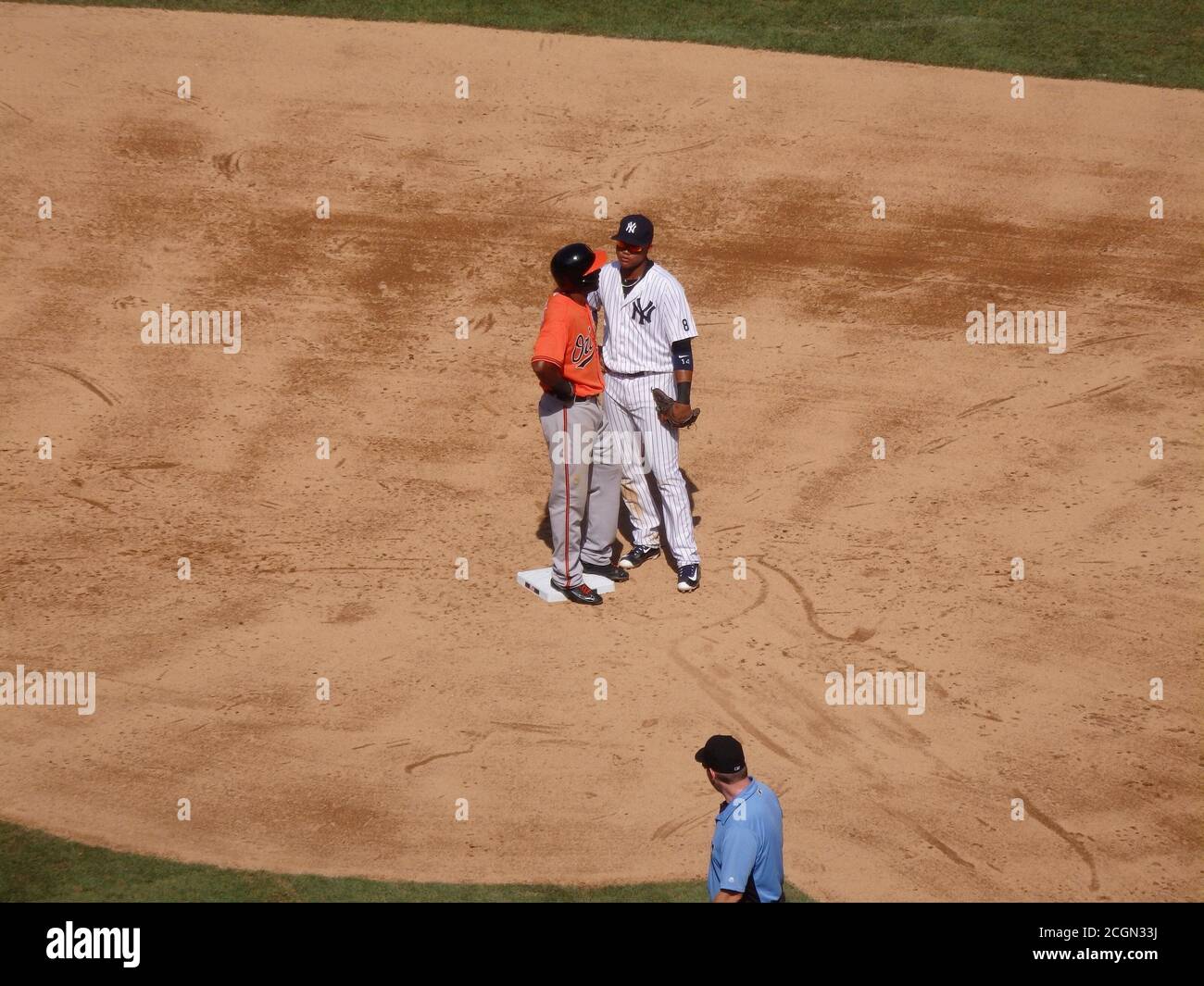 A baseball umpire watches 2nd base as two baseball players have a discussion, Yankee Stadium, New York City, United States Stock Photo