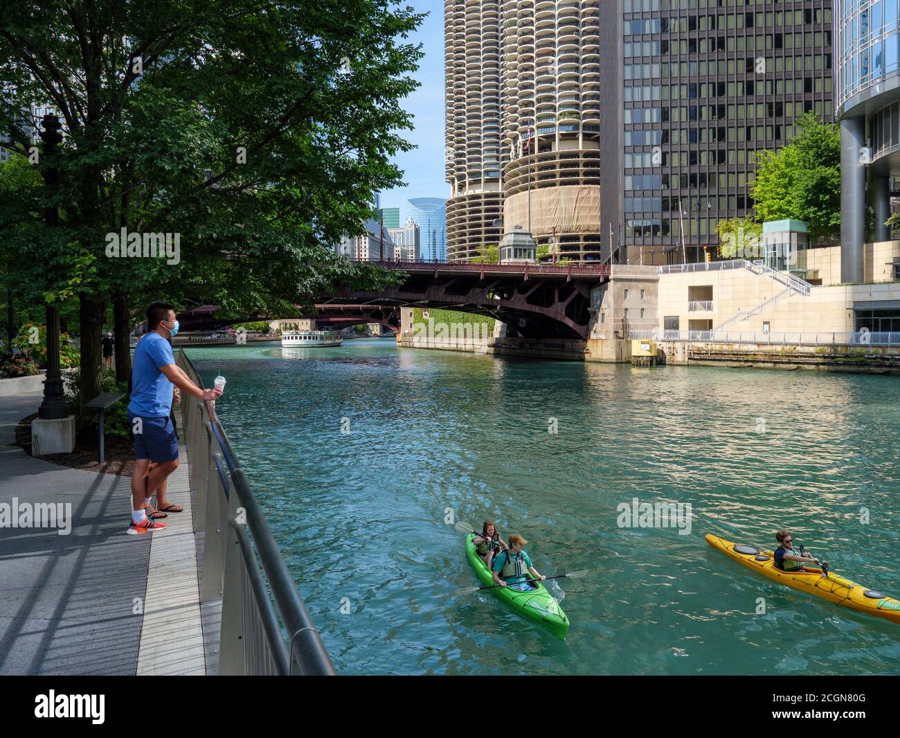 Man wearing face mask  enjoying the view from Chicago Riverwalk during COVID pandemic, kayakers on Chicago River. Stock Photo
