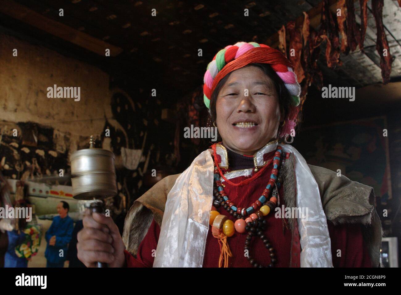 Tibetan woman at home with prayer wheel, Muli Tibetan Autonomous County, west Sichuan, China 15th Dec 2006 Stock Photo