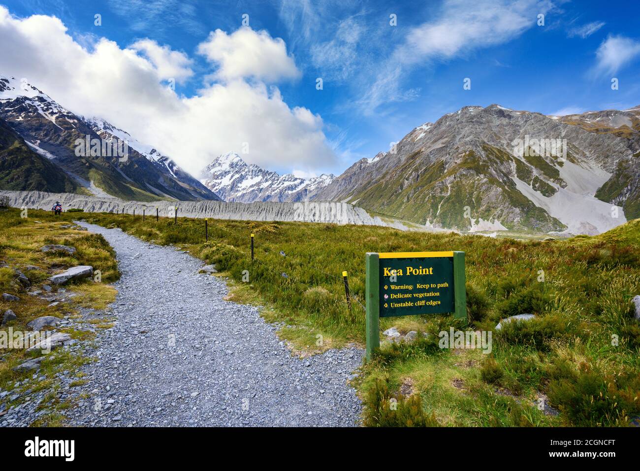 Signs and paths to view points at the Kea Point Track in Mount Cook National Park, high rocky mountains and green grass in summer in New Zealand. Stock Photo