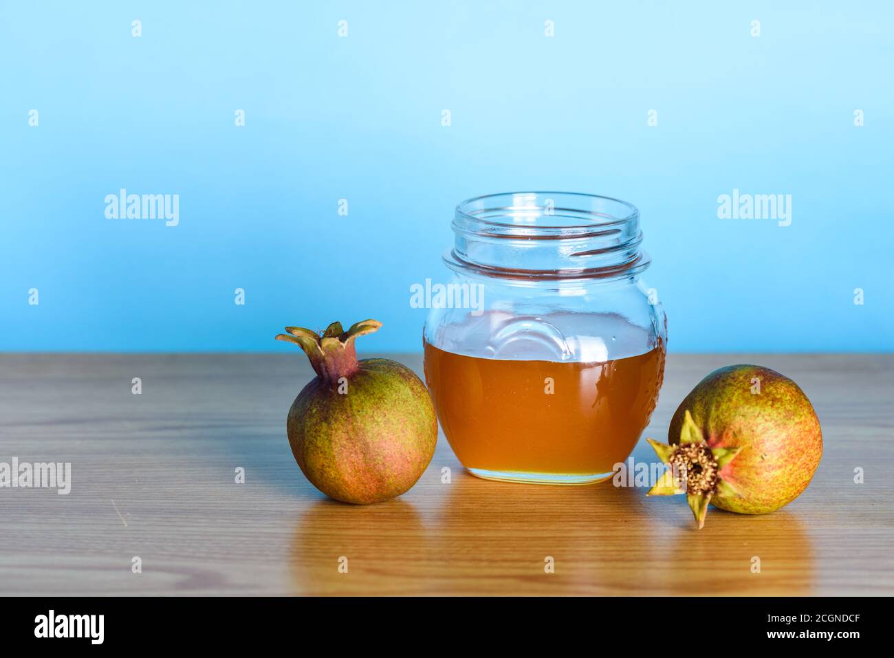Rosh Ha Shana - Jewish new year composition of pomegranate and jar of honey for Rosh Hashanah on wooden table over blue background.Greeting card with copy space. Stock Photo
