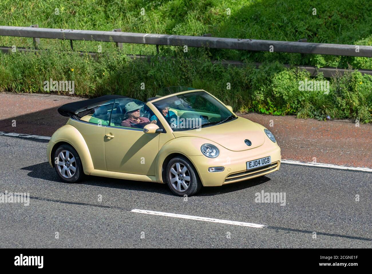 2004 yellow faded paint on VW Volkswagen Beetle Cabriolet; Vehicular traffic moving vehicles, driving vehicle on UK roads, motors, motoring on the M6 motorway highway Stock Photo