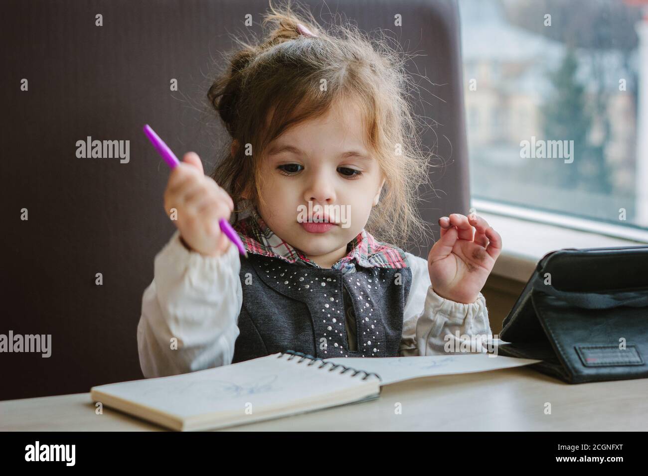 Little kid girl writing or drawing with pen in scetch book Stock Photo ...