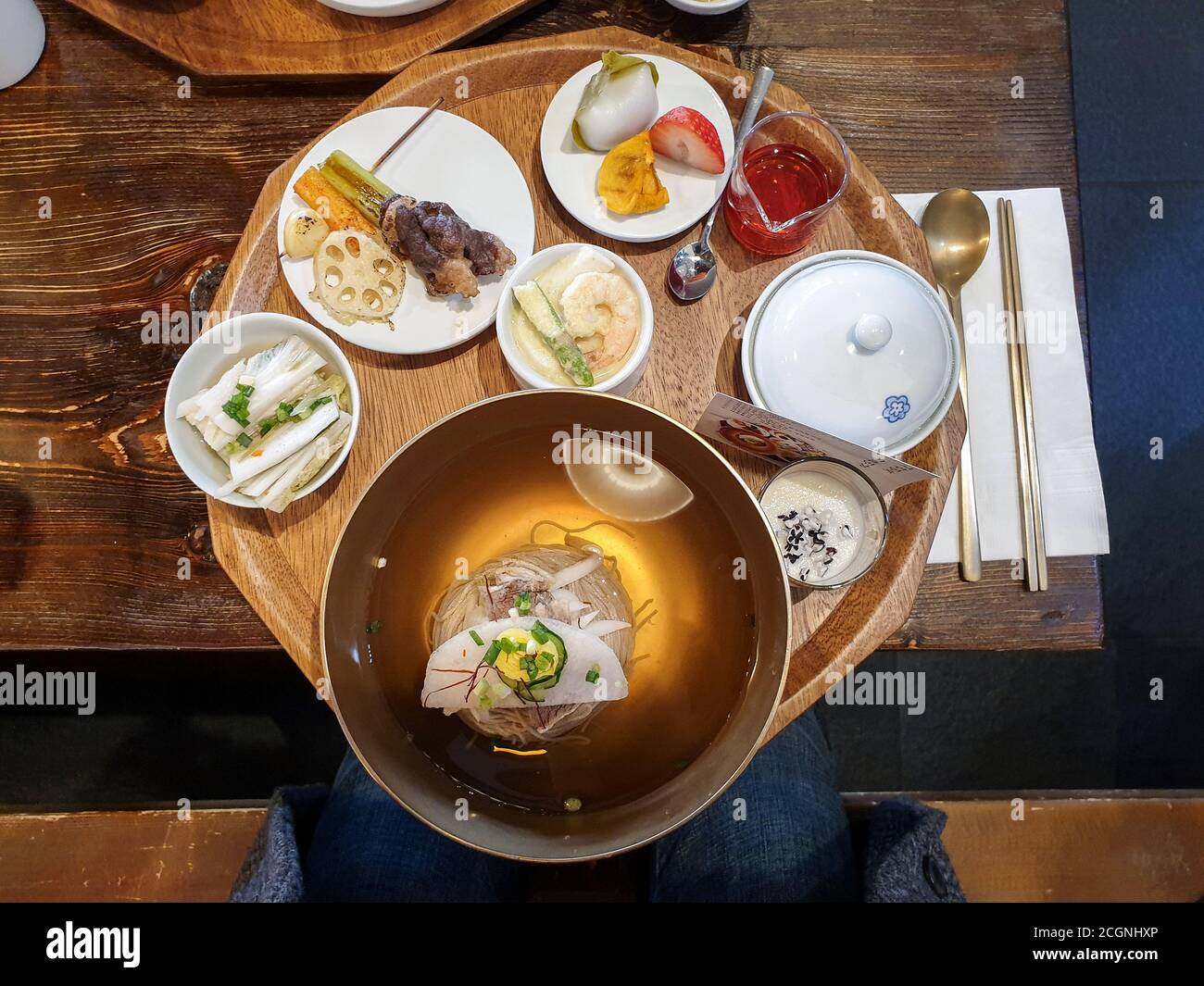 Various kinds of Korean traditional food set on table. Pyongyang naengmyeon, chilled buckwheat noodle soup. Fried lotus root and grilled brisket. Stock Photo