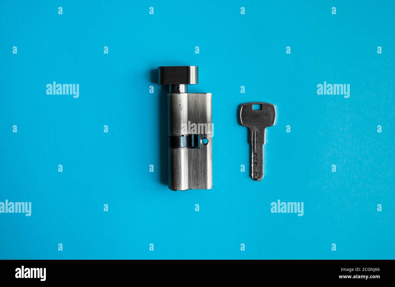 A door lock cylinder core with key on the blue background. The cylinder