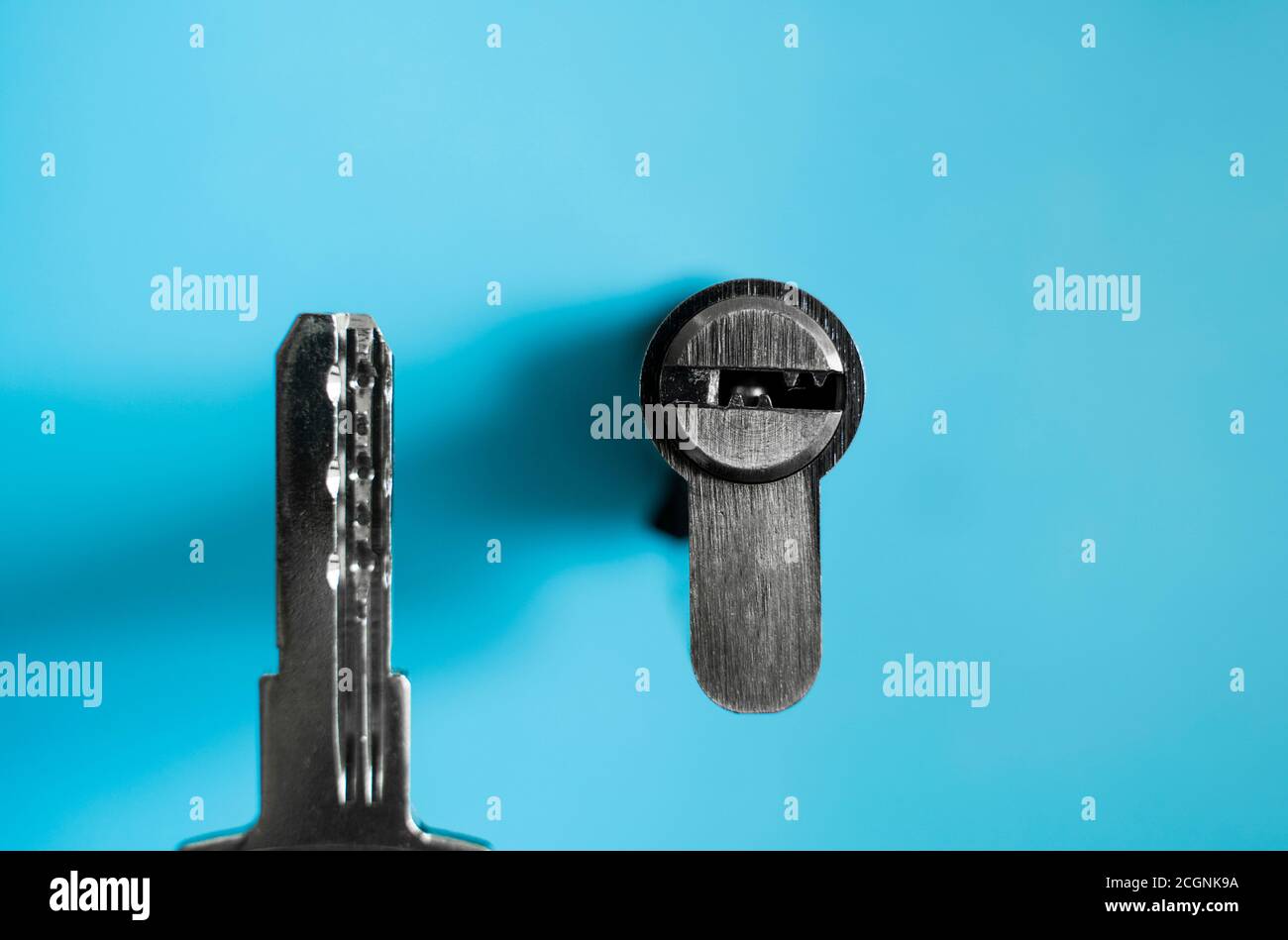 A door lock cylinder core with key on the blue background. The cylinder