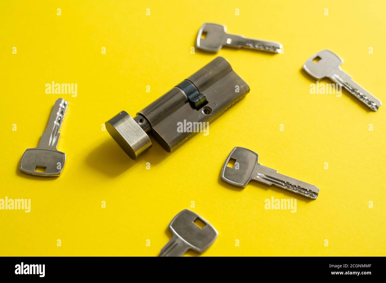 A door lock cylinder core with keys on the yellow background. The