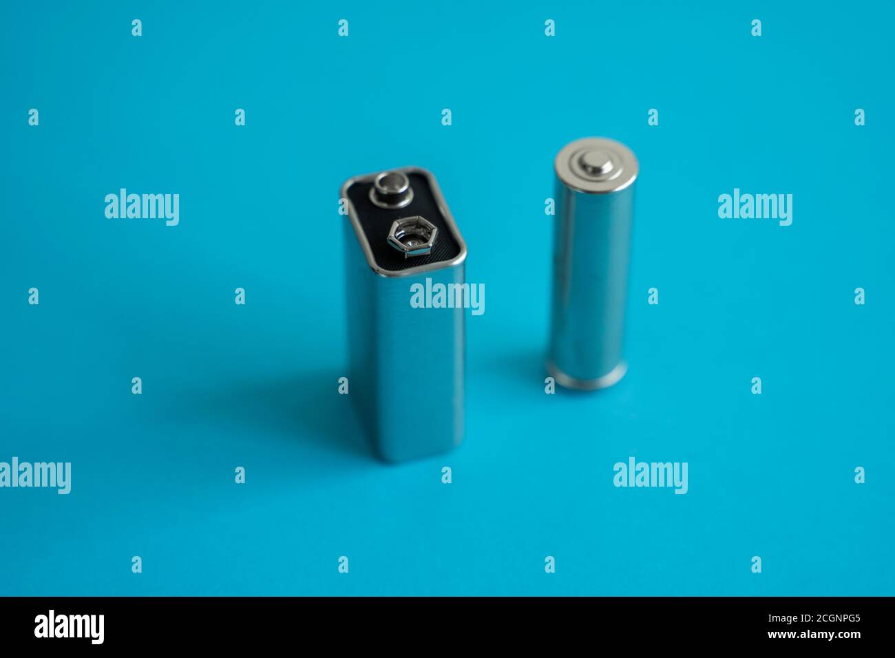 High voltage Volt 9V battery and alkaline AA battery on a blue