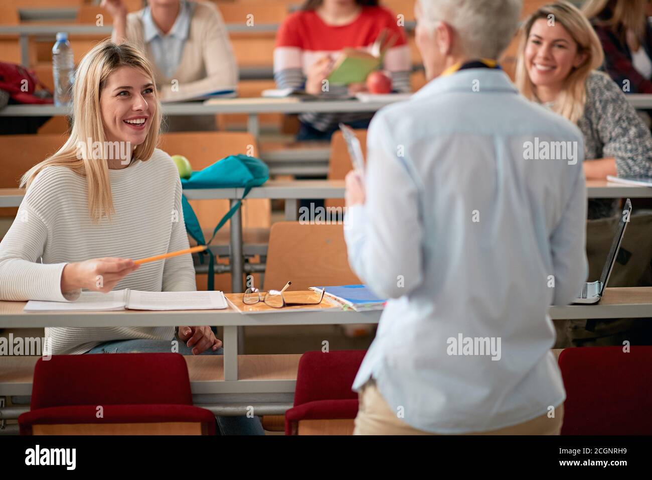 A female student talking to a professor at a lecture in an amphitheatre ...