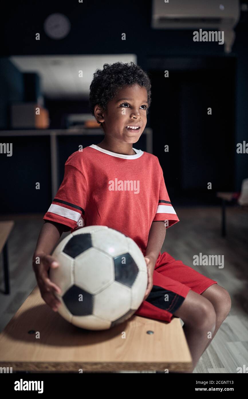 A little soccer player in a locker room posing ready for a training Stock Photo