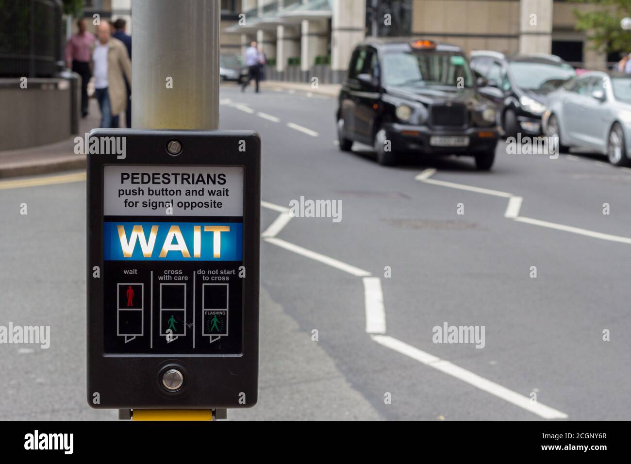 Illuminated 'Wait' pedestrian sign at a pedestrian crossing on a busy road in central London, England, UK Stock Photo