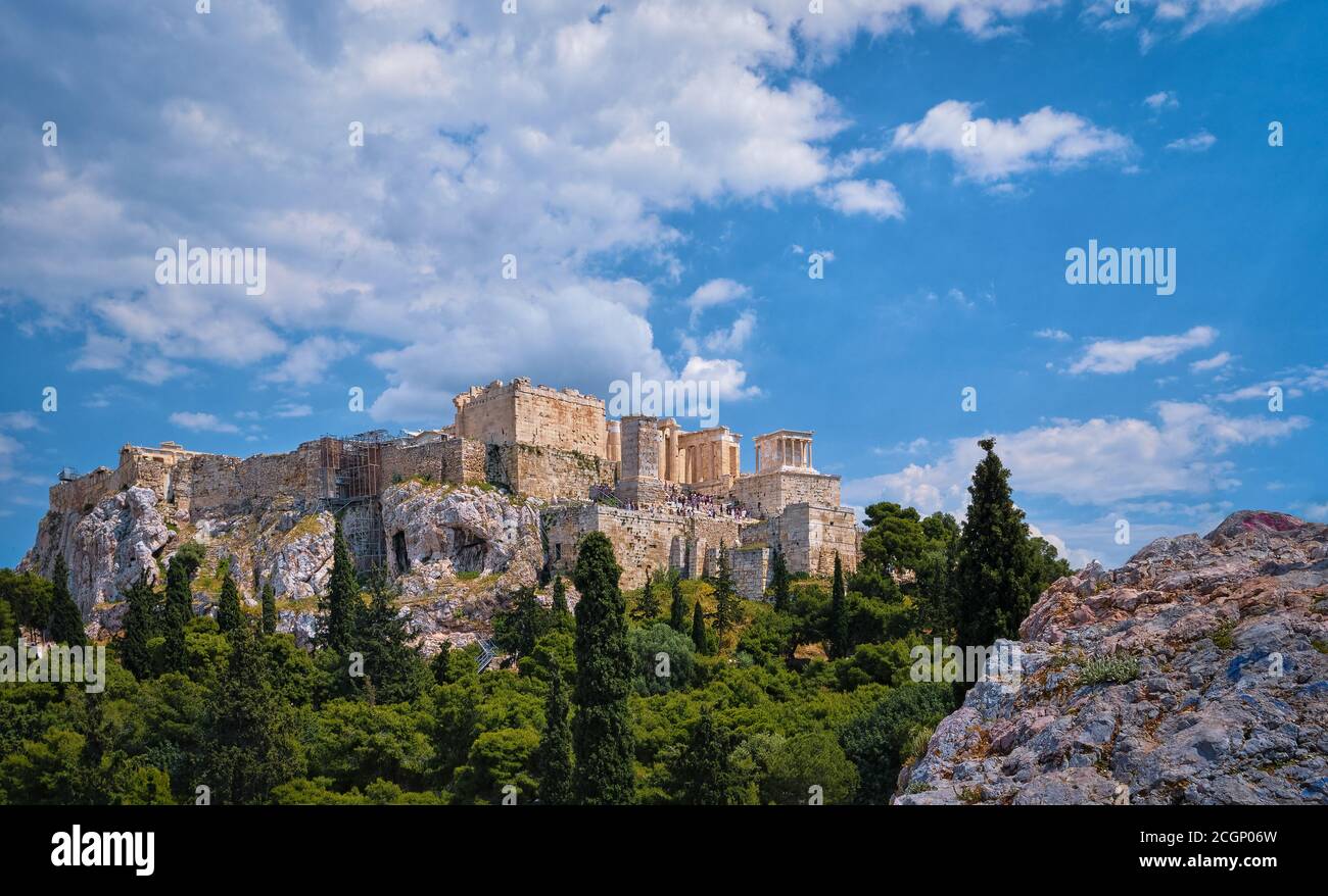 View of Acropolis hill from Areopagus hill on summer day with great clouds in blue sky, Athens, Greece. UNESCO heritage. Propylaea gate, Parthenon. Stock Photo