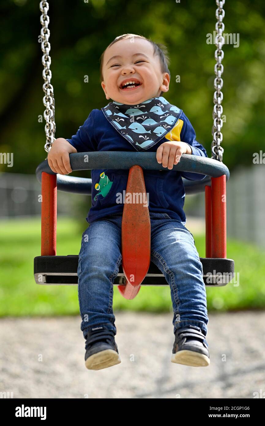 Toddler, boy, 14 months, multi-ethnic, on children's swing, laughs, Blaubeuren, Baden-Wuerttemberg, Germany Stock Photo