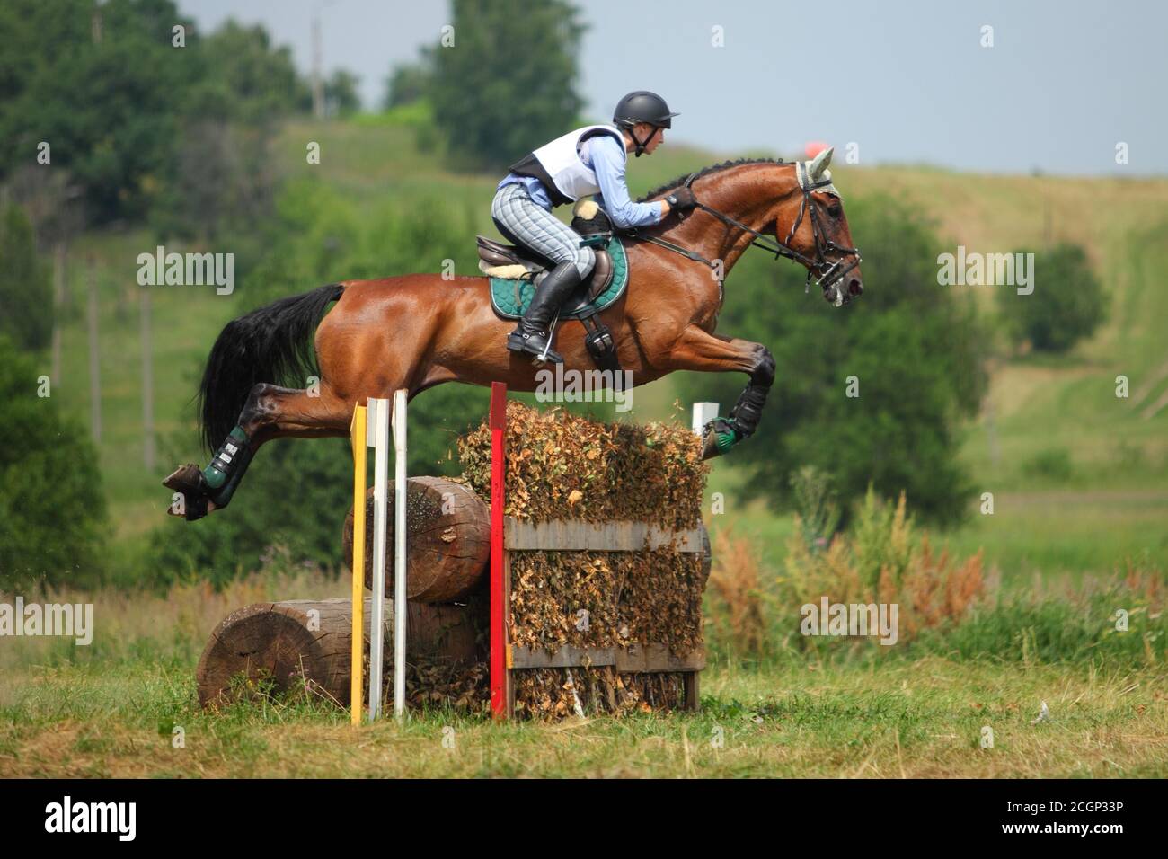 Sports horse and teen rider sailing over a jump at an outdoor equestrian competition Stock Photo