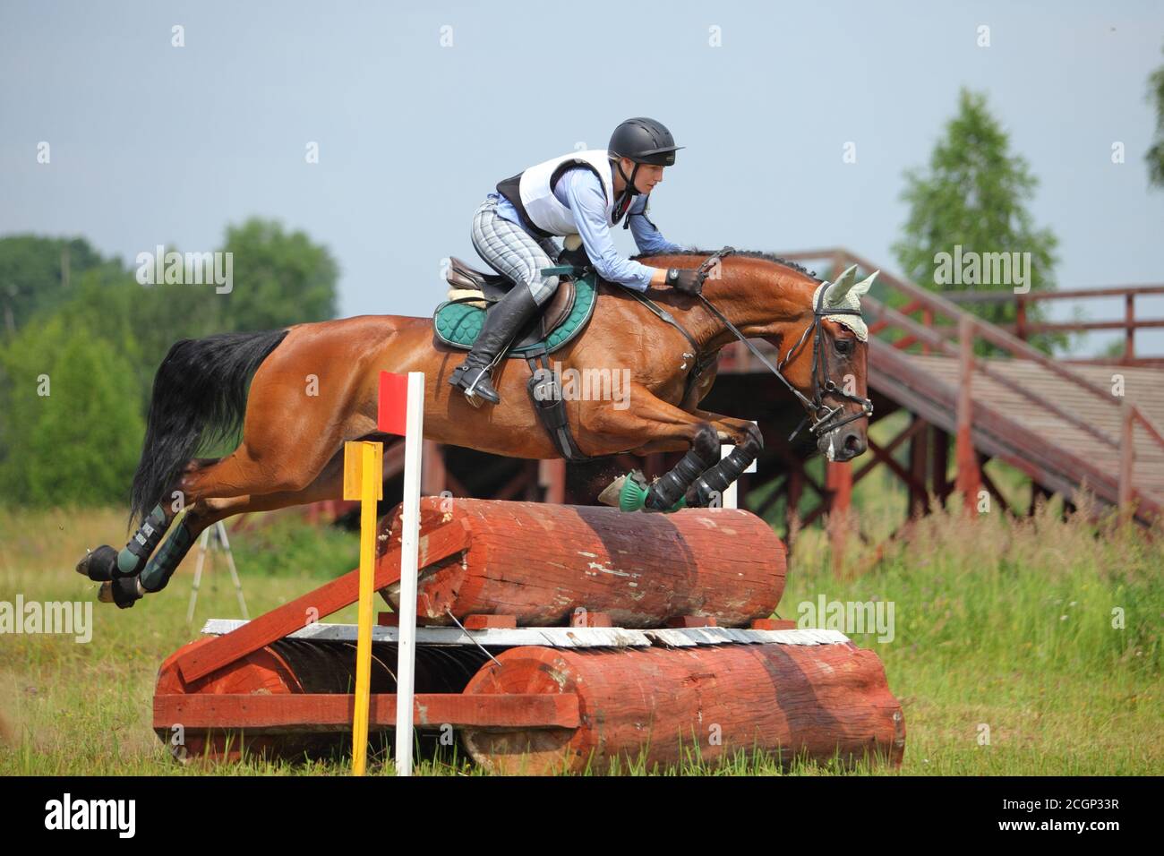 Sports horse and teen rider sailing over a jump at an outdoor equestrian competition Stock Photo