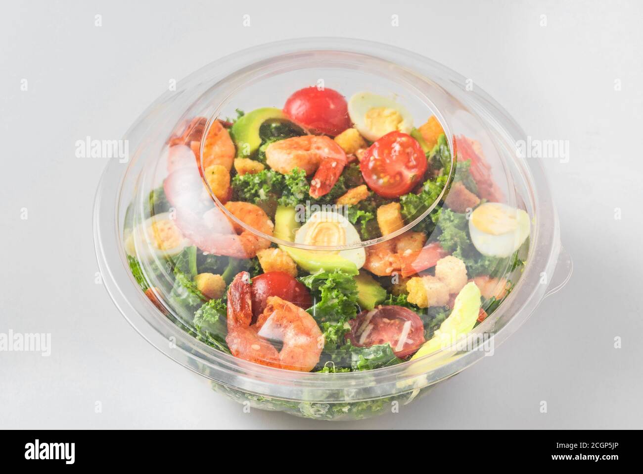 Plastic package with healthy shrimp caesar salad with avocado , kale, tomatoes and eggs to take away. close up. mediterranean diet Stock Photo