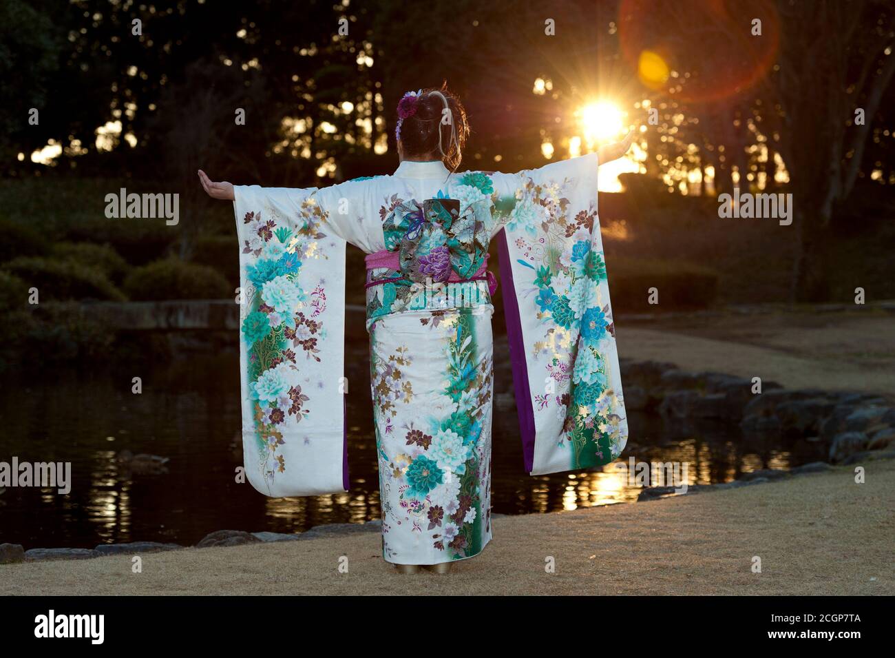 Japanese teenager wearing traditional kimono back and arms outstretched with beautiful flare and sunshine celebrating the Coming of Age Day. Stock Photo