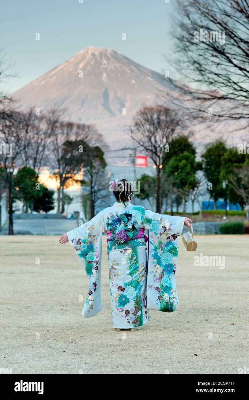 Japanese teenager wearing traditional kimono with arms outstretched contemplating the beauty of Mt. Fuji celebrating the Coming of Age Day. Stock Photo