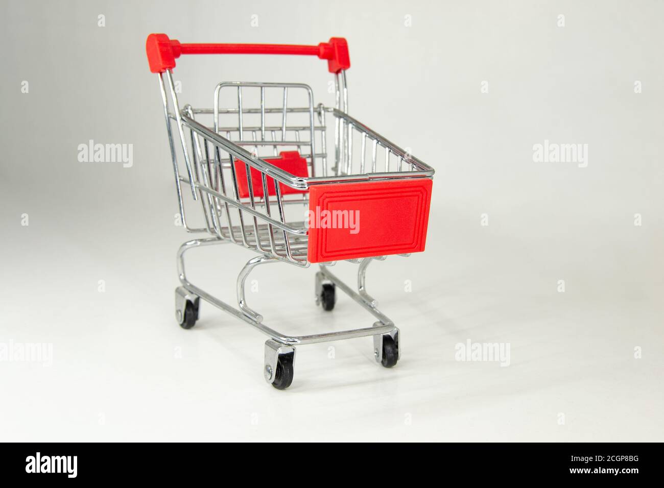 Realistic iron mini shopping cart with red plastic parts. Object for purchases such as sales, Black Friday or Christmas shopping. White background. Stock Photo