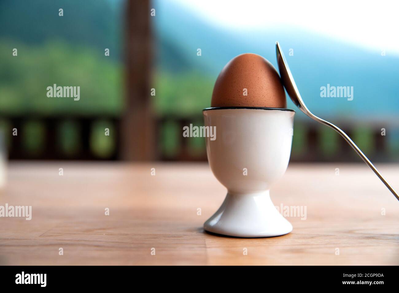 boiled egg in eggcup on wooden table outside, breakfast eggin white egg cup Stock Photo