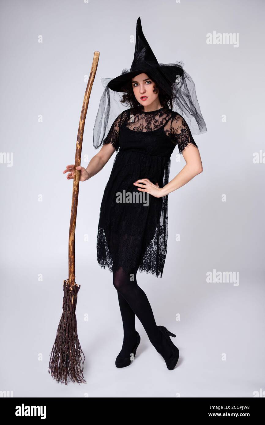 full length portrait of woman in black witch halloween costume and hat