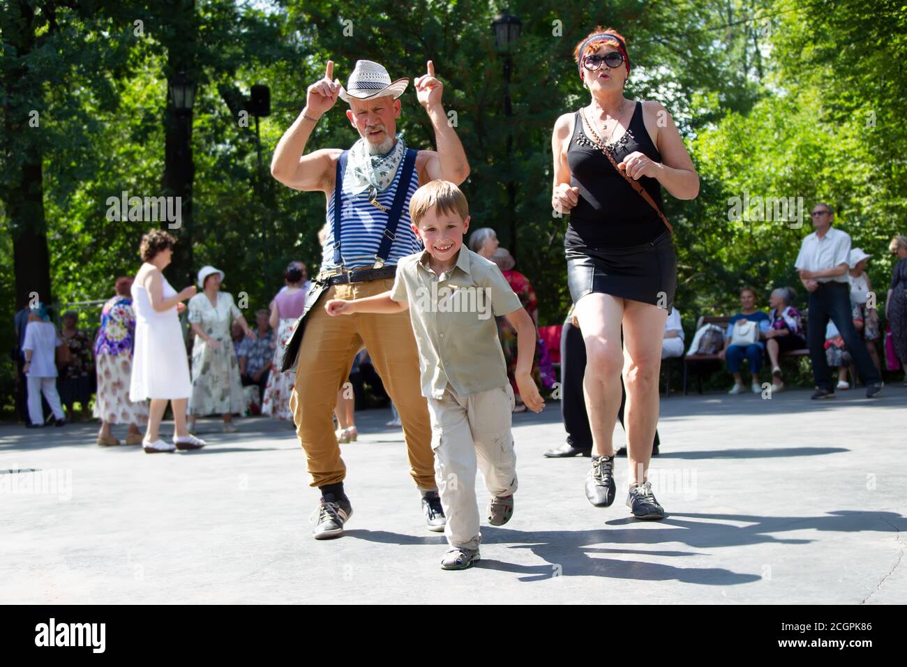 Cheerful grandparents are dancing with their grandson. Stock Photo