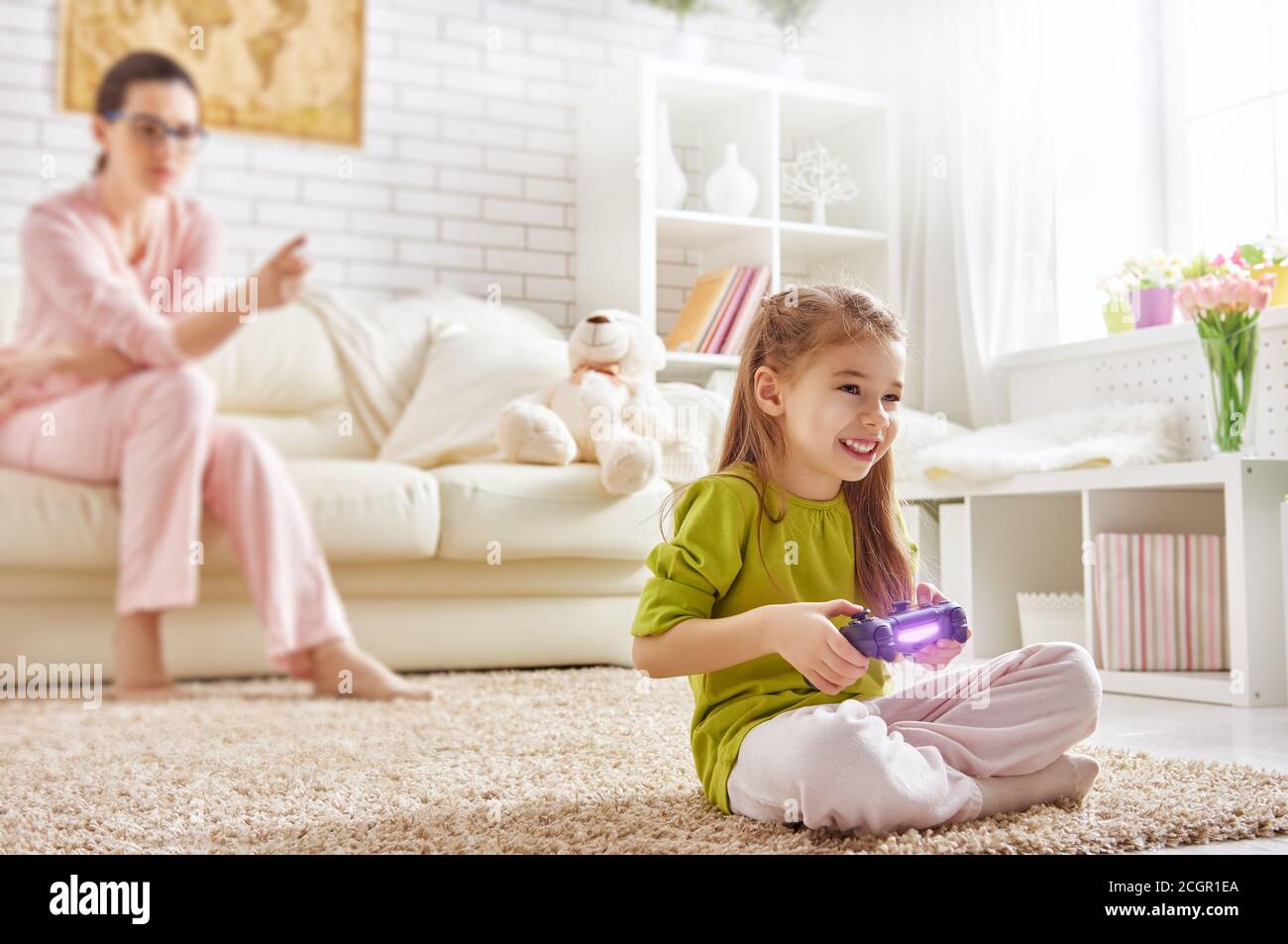 happy child girl playing video games. mother frustrating that her child playing video games Stock Photo