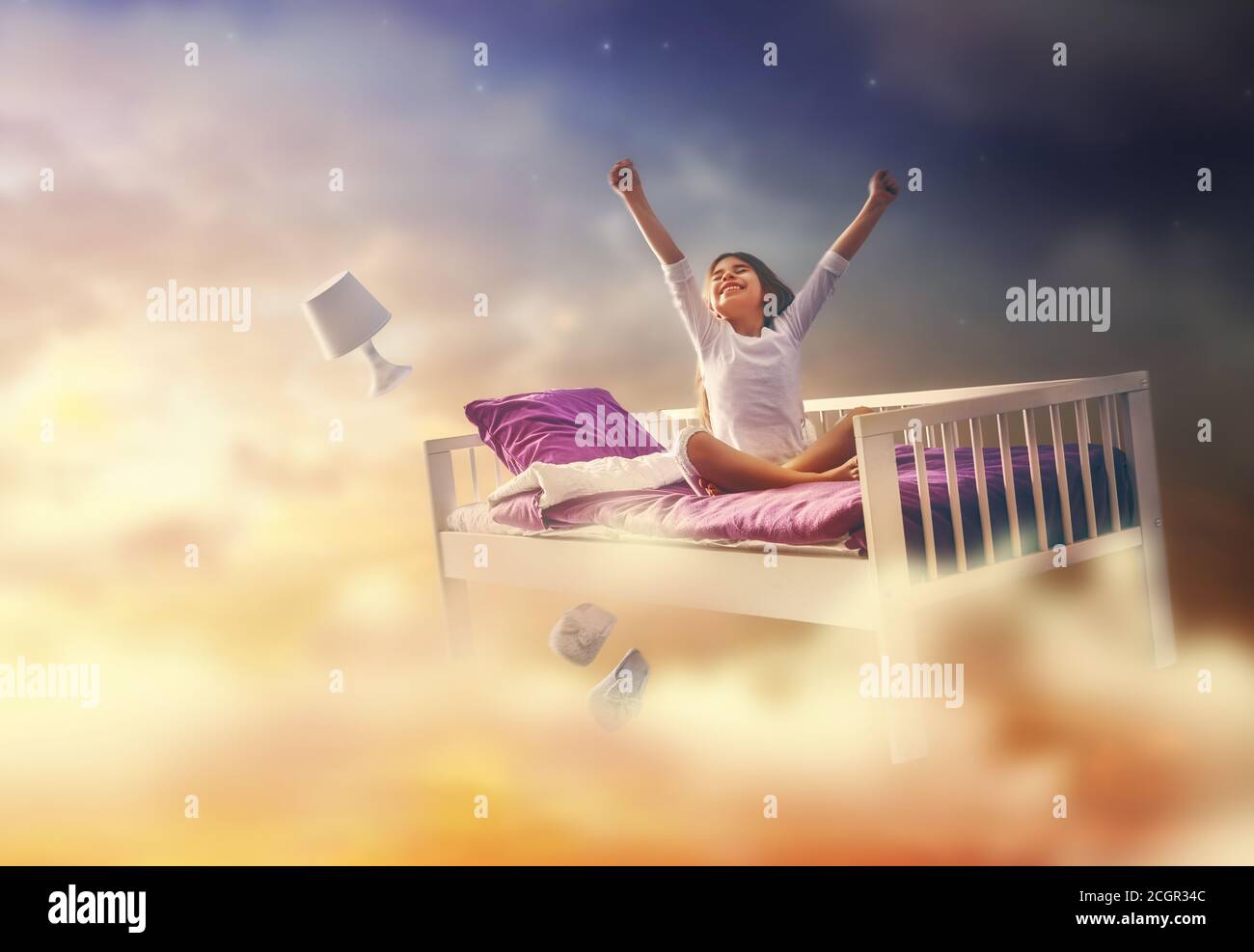 Kids dreams. Cute child girl is flying in her bed trough star sky Stock