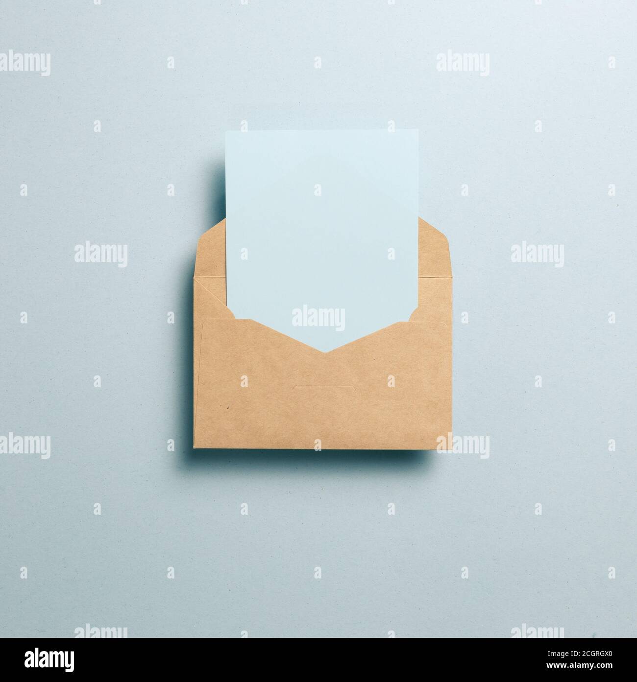 Empty card in kraft envelope on blue background. top view, copy space Stock Photo